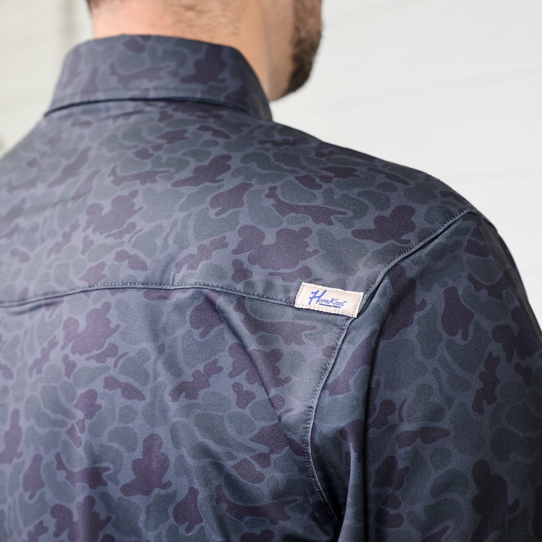 Patterned shirt with a brand label on  the vent neutral background