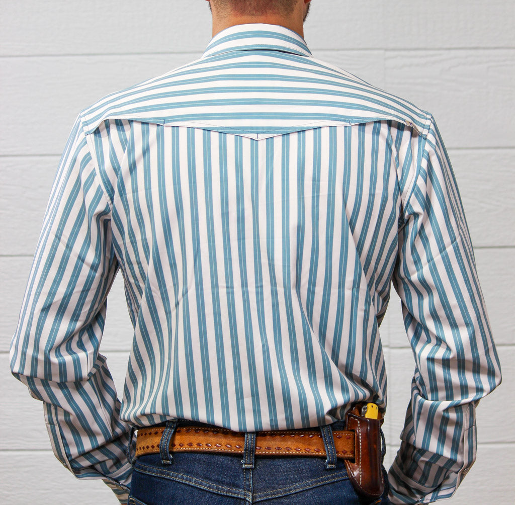 A man viewed from behind wearing a light blue and white vertically striped western-style shirt, paired with a brown leather belt and jeans against a white wood-paneled wall.