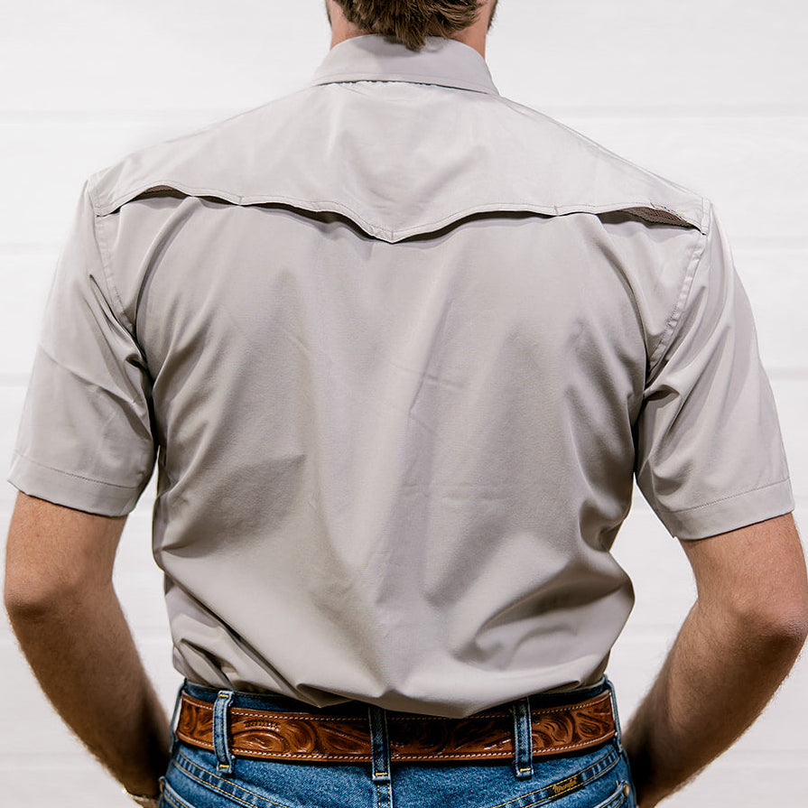 Man wearing a light gray shirt and blue jeans with a brown belt against a white background. back facing