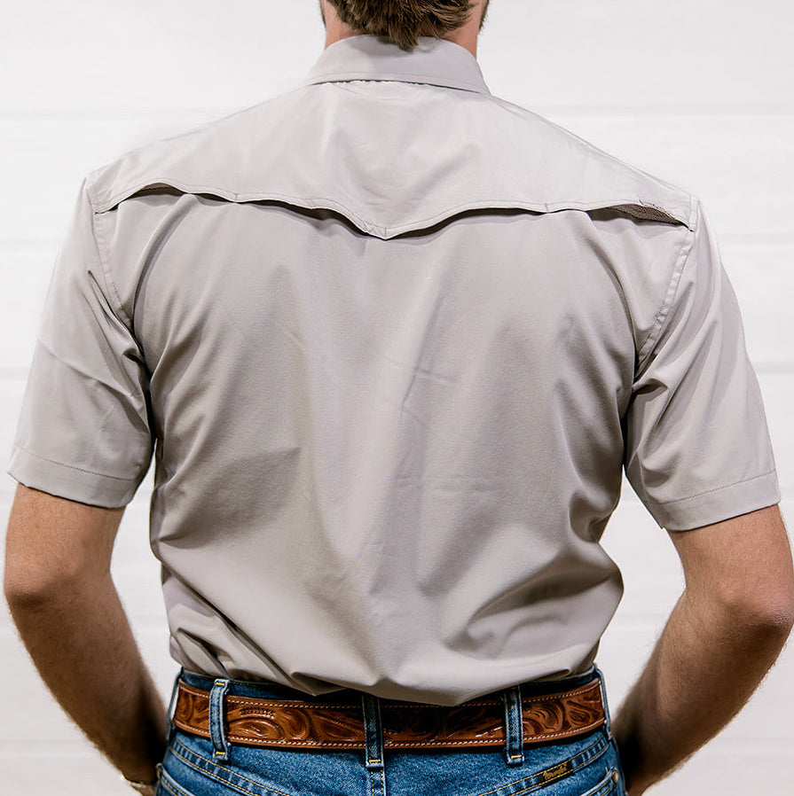 Man wearing a light gray shirt and blue jeans with a brown belt against a white background. back facing