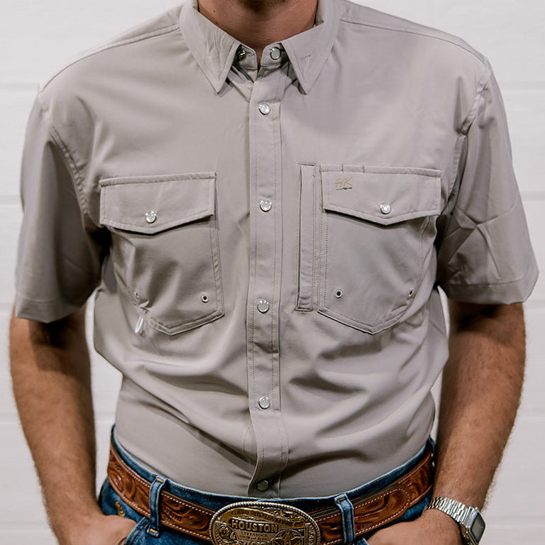 Man wearing a light gray shirt and blue jeans with a white background. Front Facing. 