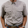 Man wearing a light gray shirt and blue jeans with a white background. Front Facing. 