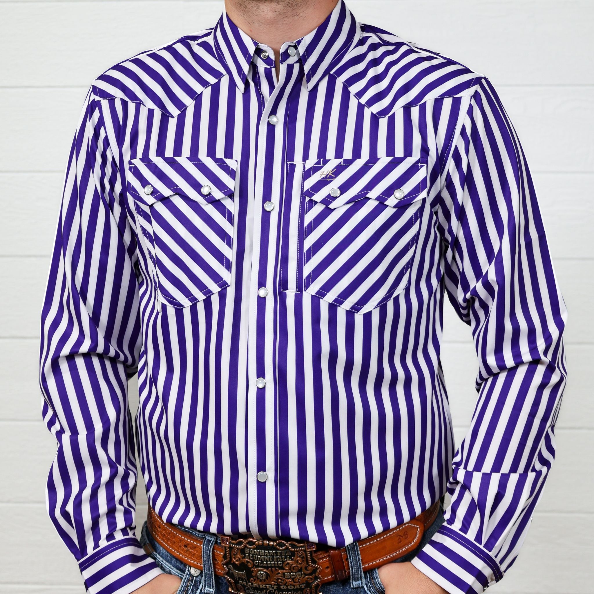 Purple and white striped  longsleeve shirt worn by a person against a white wall.