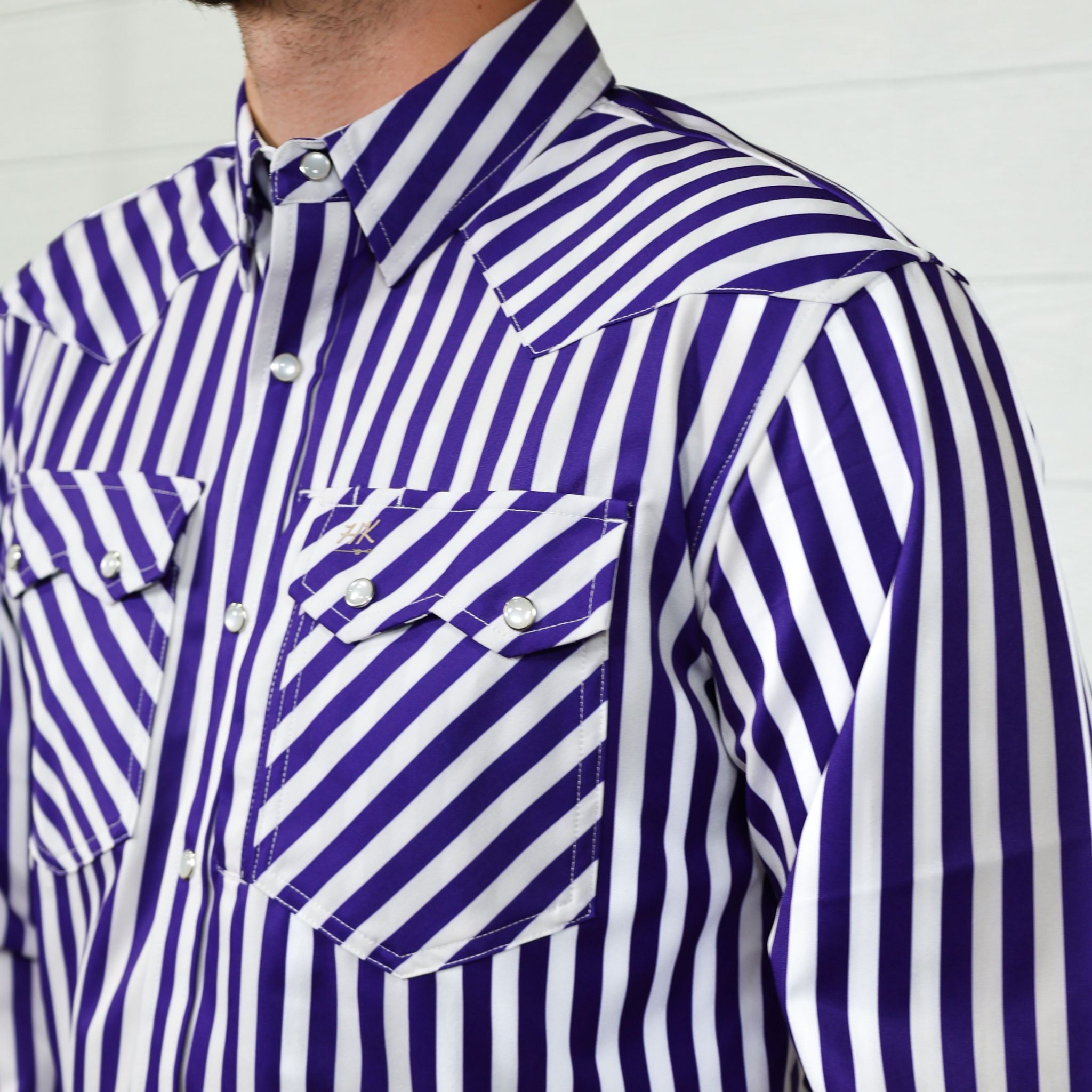 Close-up of a person wearing a purple and white striped shirt against a plain background, showing the sawtooth pocket