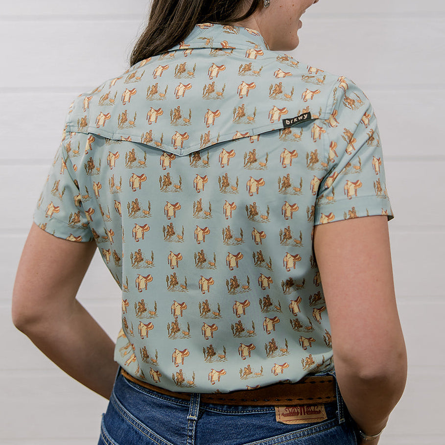 Person wearing a western patterned shirt and jeans against a plain background showing the back 