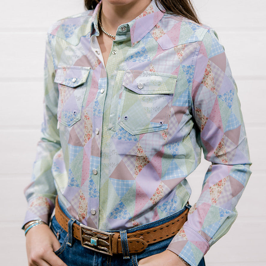Woman wearing a colorful patterned shirt with a plain background. Front facing