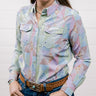 Woman wearing a colorful patterned shirt with a plain background. Front facing
