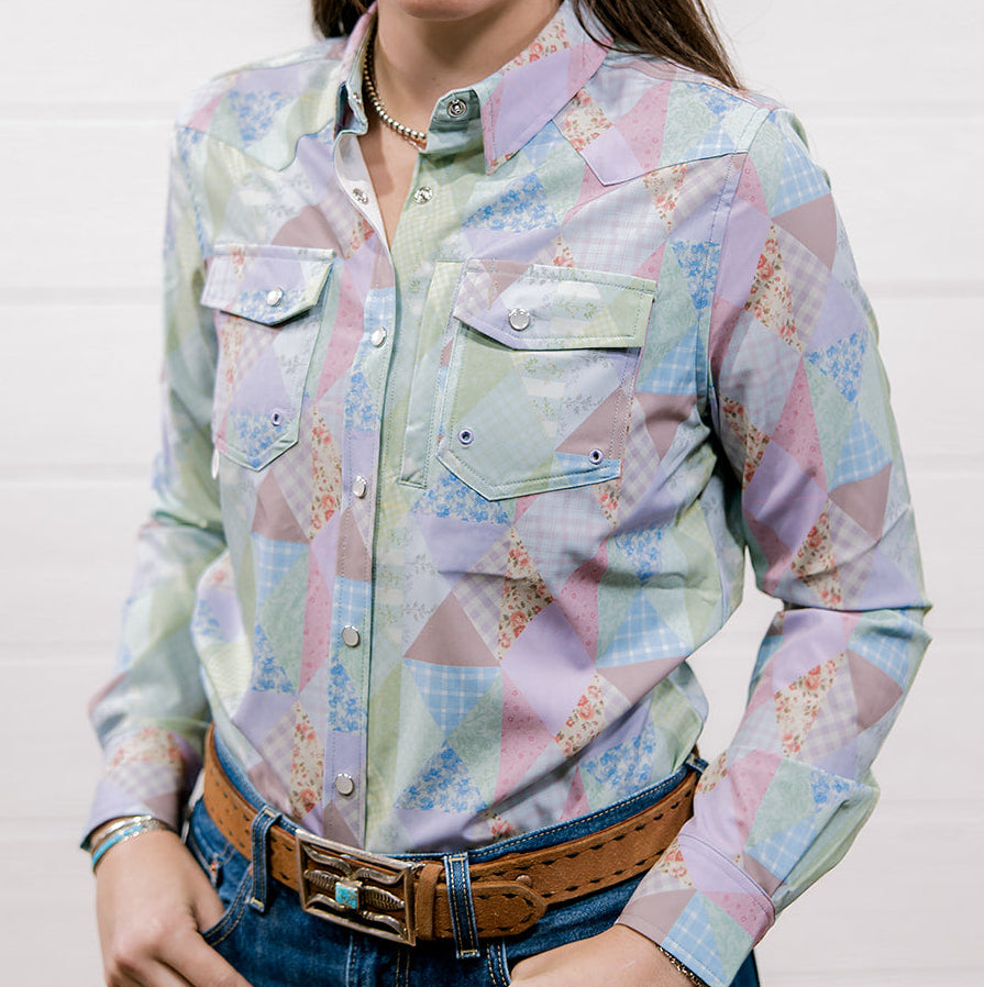 Woman wearing a colorful patterned shirt with a plain background. Front facing