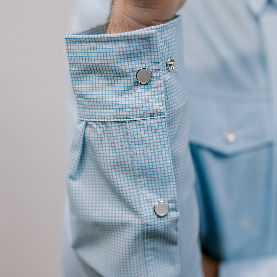 Close-up of a light blue checkered shirt with buttons on a neutral background