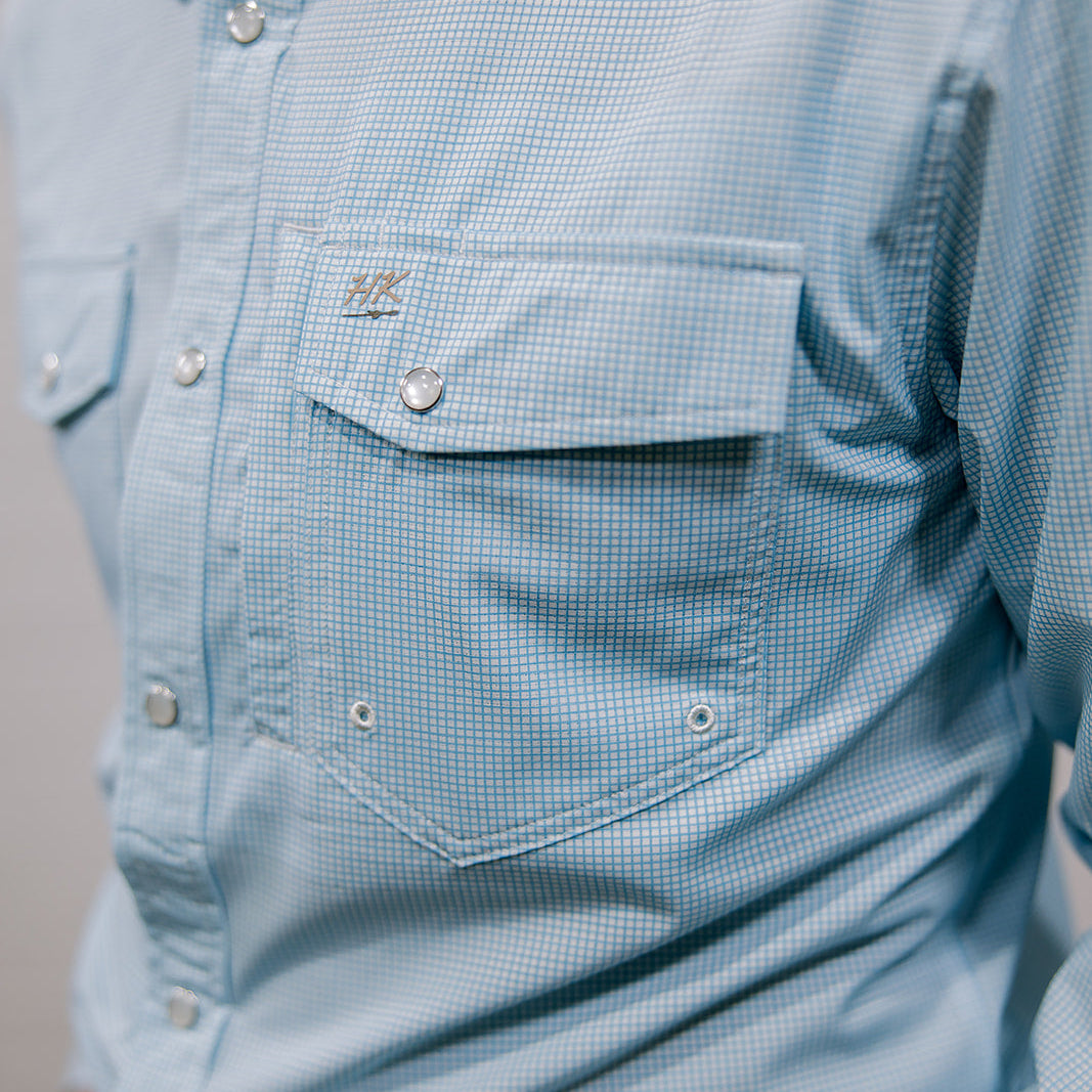 Close-up of a light blue checkered shirt with a pocket and buttons.