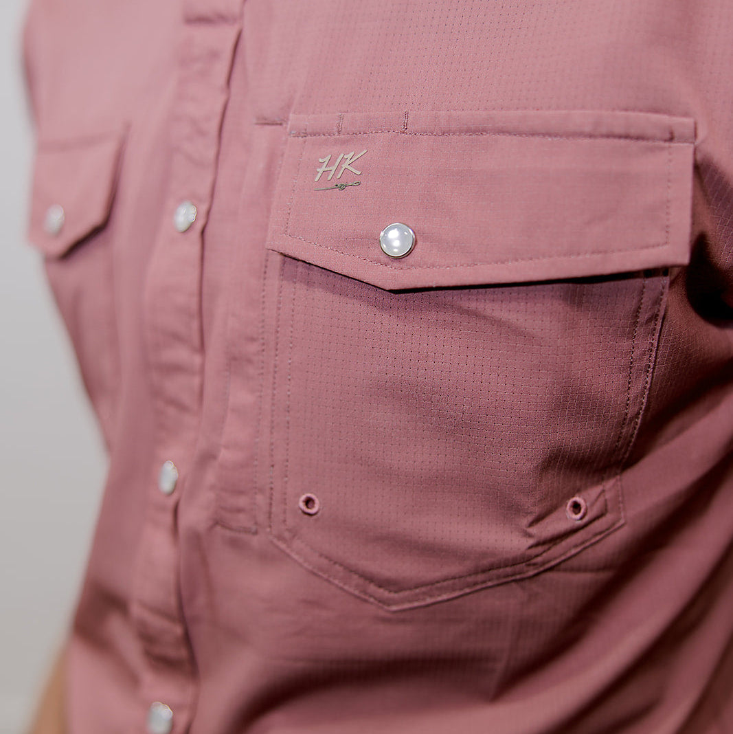 Close-up of a mauve rangevent button-up shirt with a brand logo on the chest pocket.
