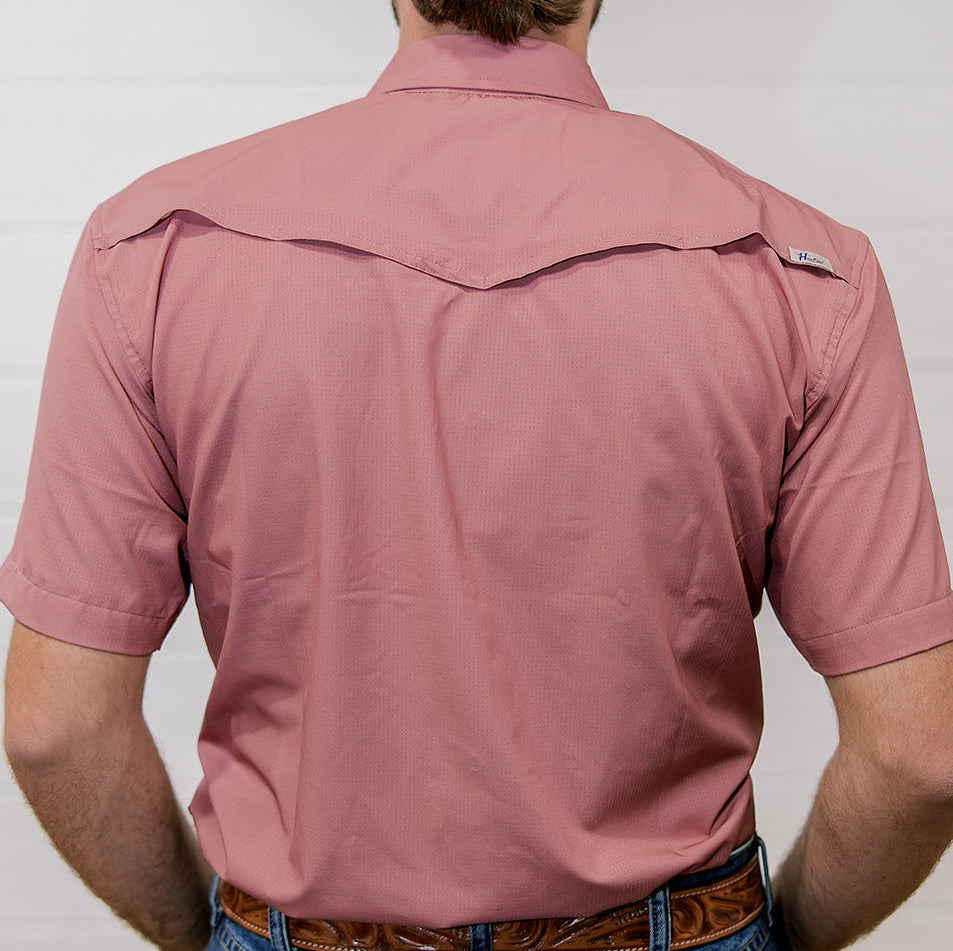 Person wearing a rangevent mauve short sleeve shirt and blue jeans against a plain background