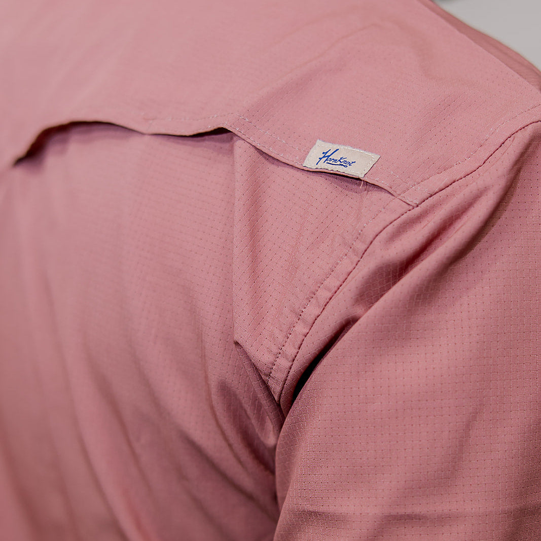Close-up of a mauve rangevent shirt with a brand label on a plain background