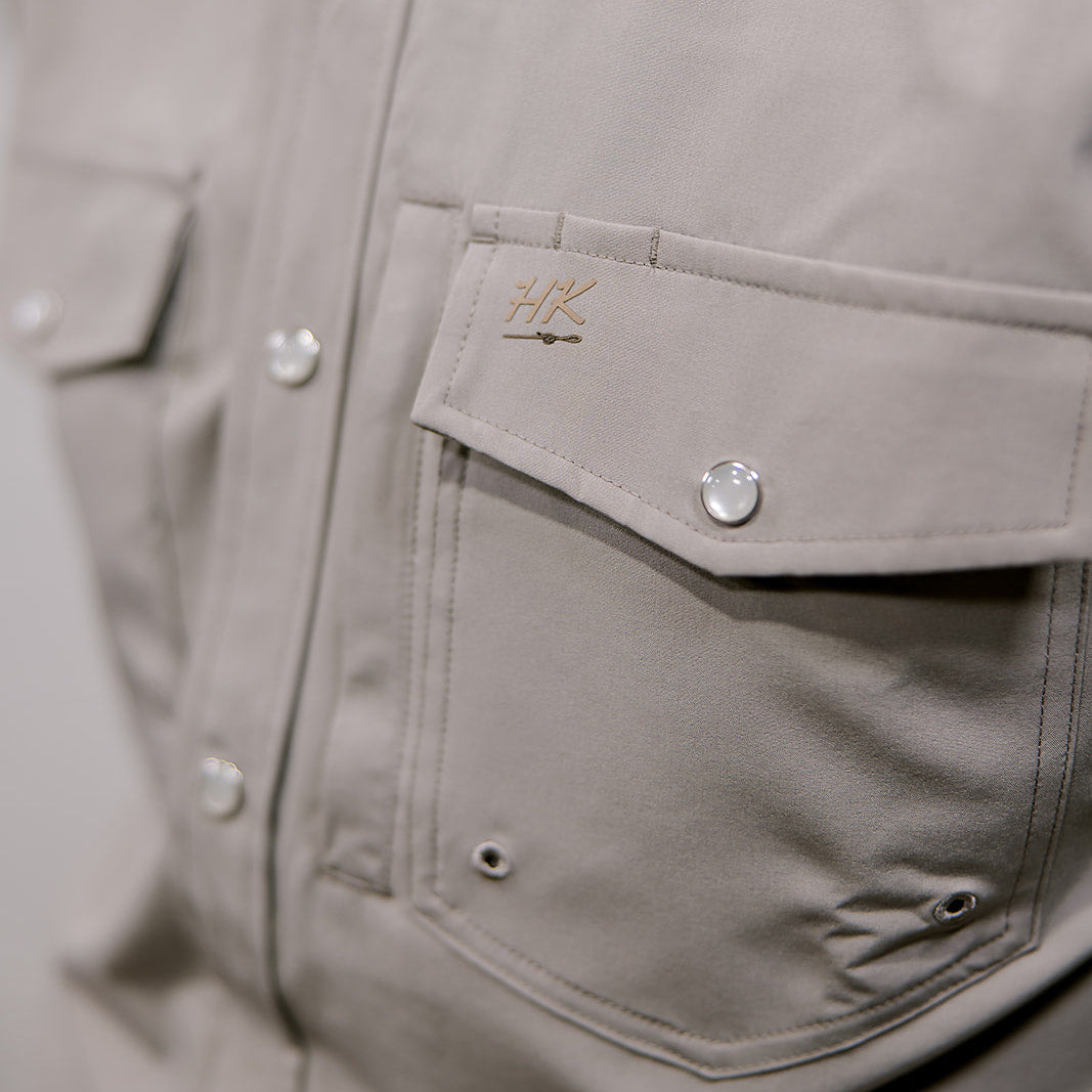 Close-up of a gray jacket with a brand logo on the chest pocket.