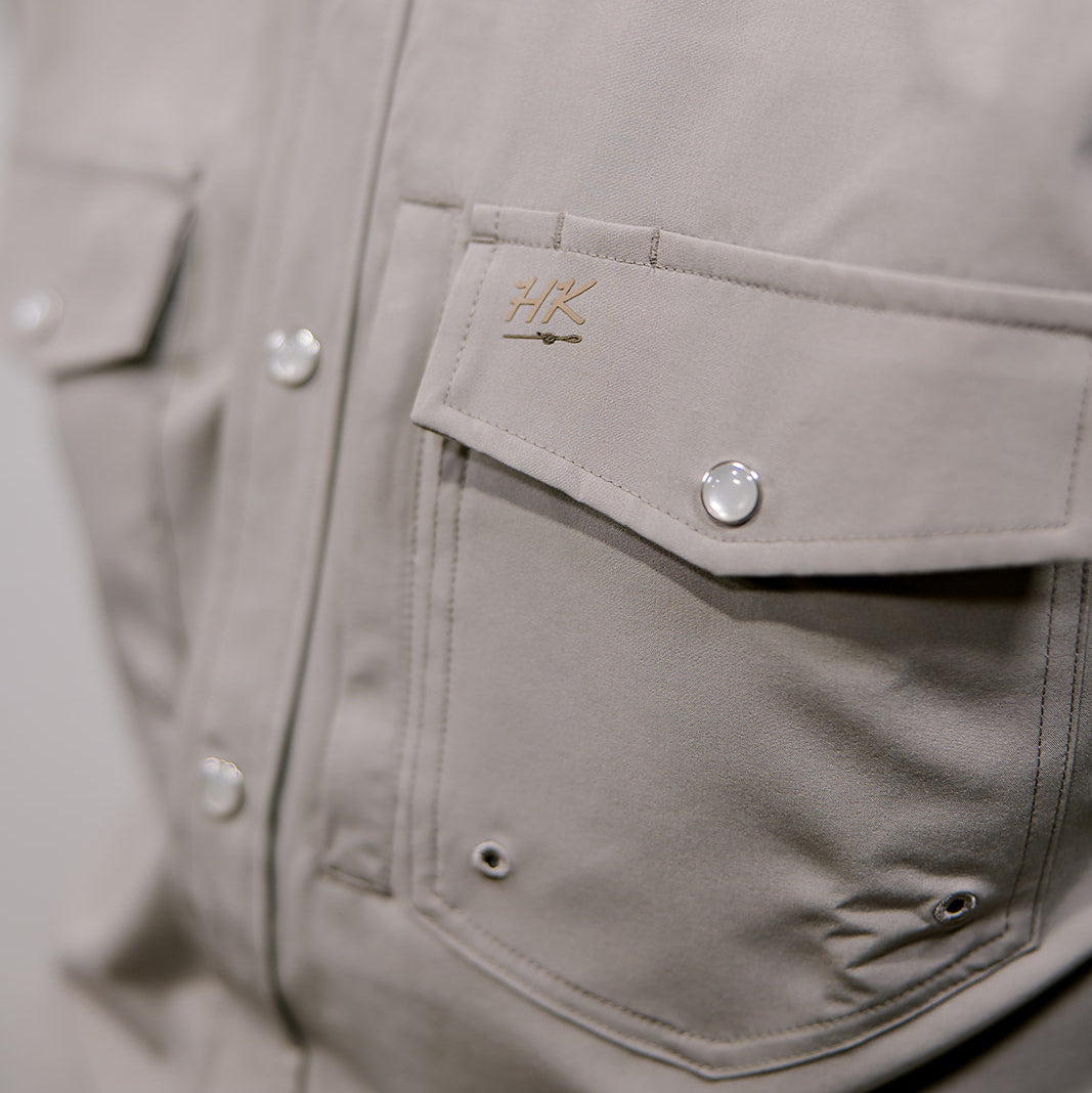 Close-up of a gray jacket with a brand logo on the chest pocket.