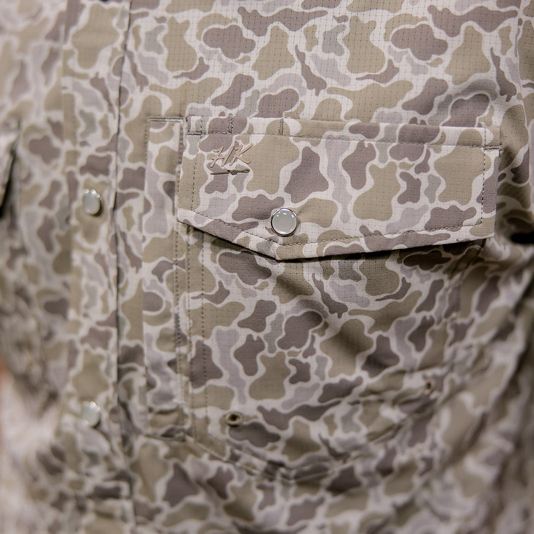 Close-up of a camouflage-patterned shirt with buttons and a pocket.