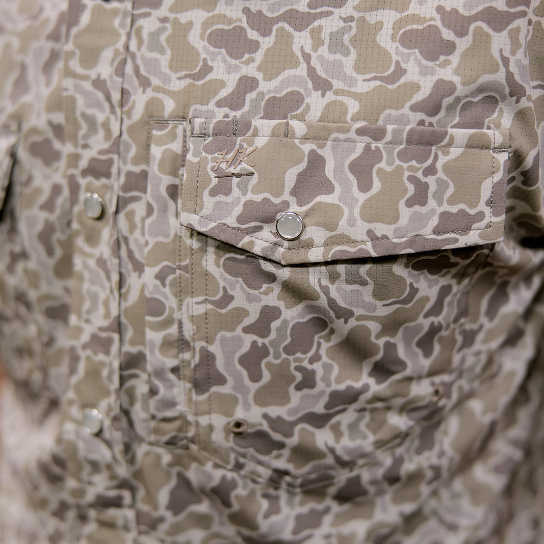 Close-up of a camouflage-patterned shirt with buttons and a pocket.