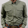 Man wearing a green shirt and blue jeans with a belt, standing against a plain background. front facing