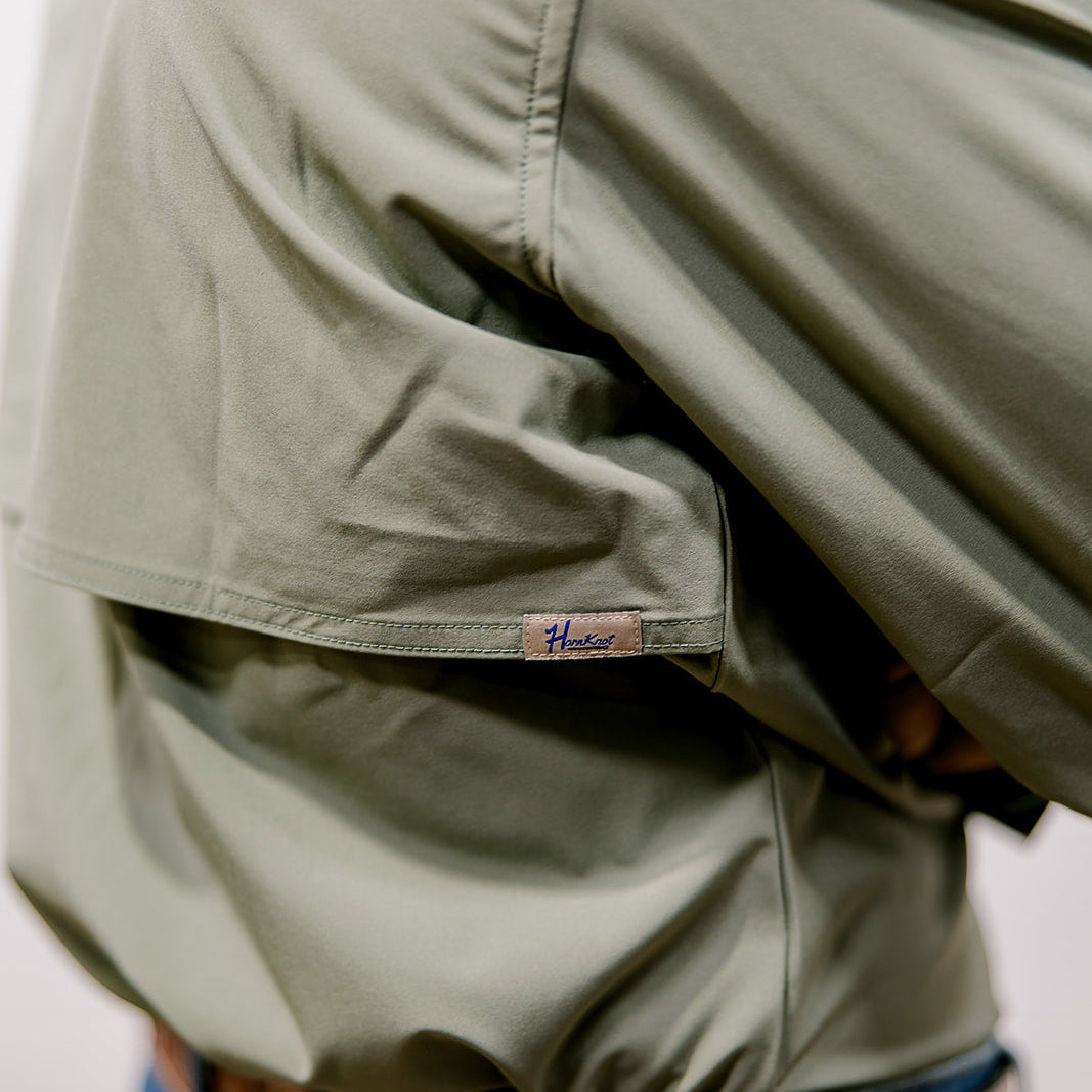 Person wearing a green shirt with a visible brand logo and blue jeans.