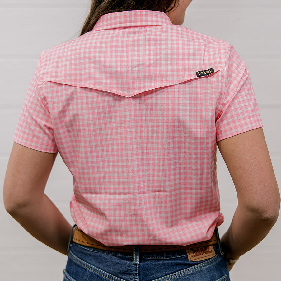 Person wearing a pink checkered shirt with a brand logo on a plain background. back facing
