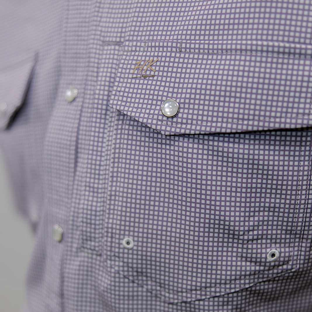 Close-up of a purple checkered shirt with a brand logo on a gray background