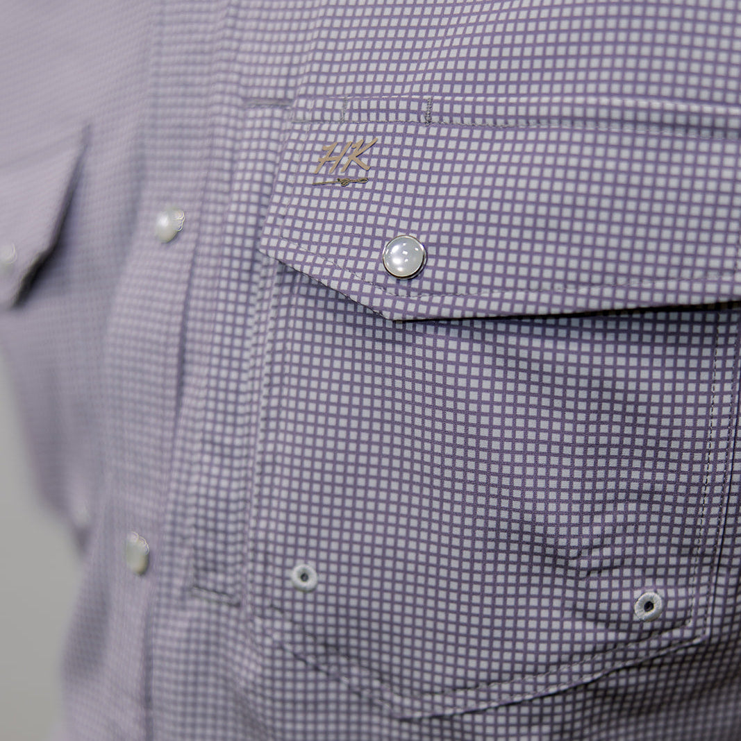 Close-up of a purple checkered shirt with a brand logo on a gray background