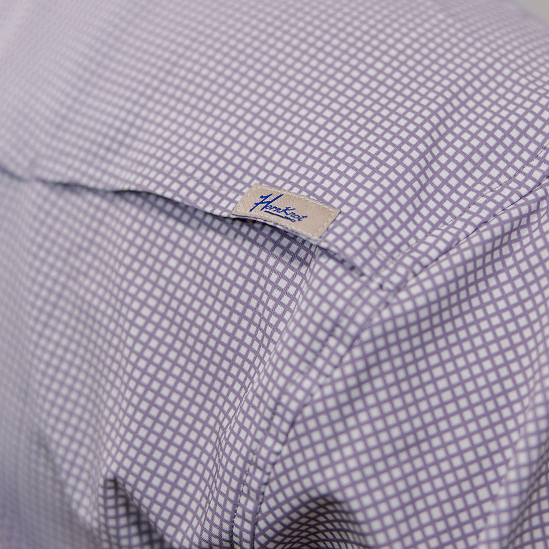 Close-up of a checkered shirt with a brand label on a white background. 