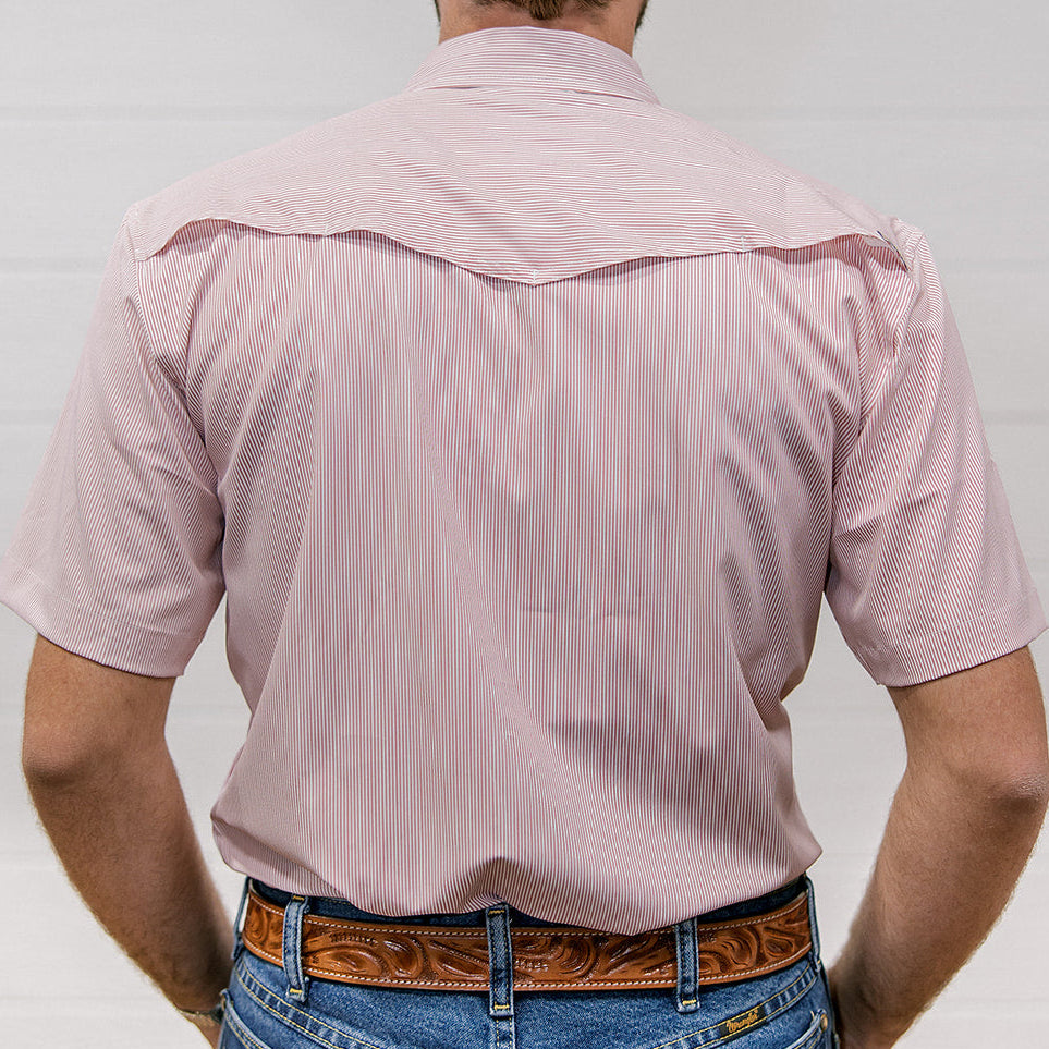 Man wearing a light pink shirt and blue jeans with a brown belt on a plain background. back facing. 