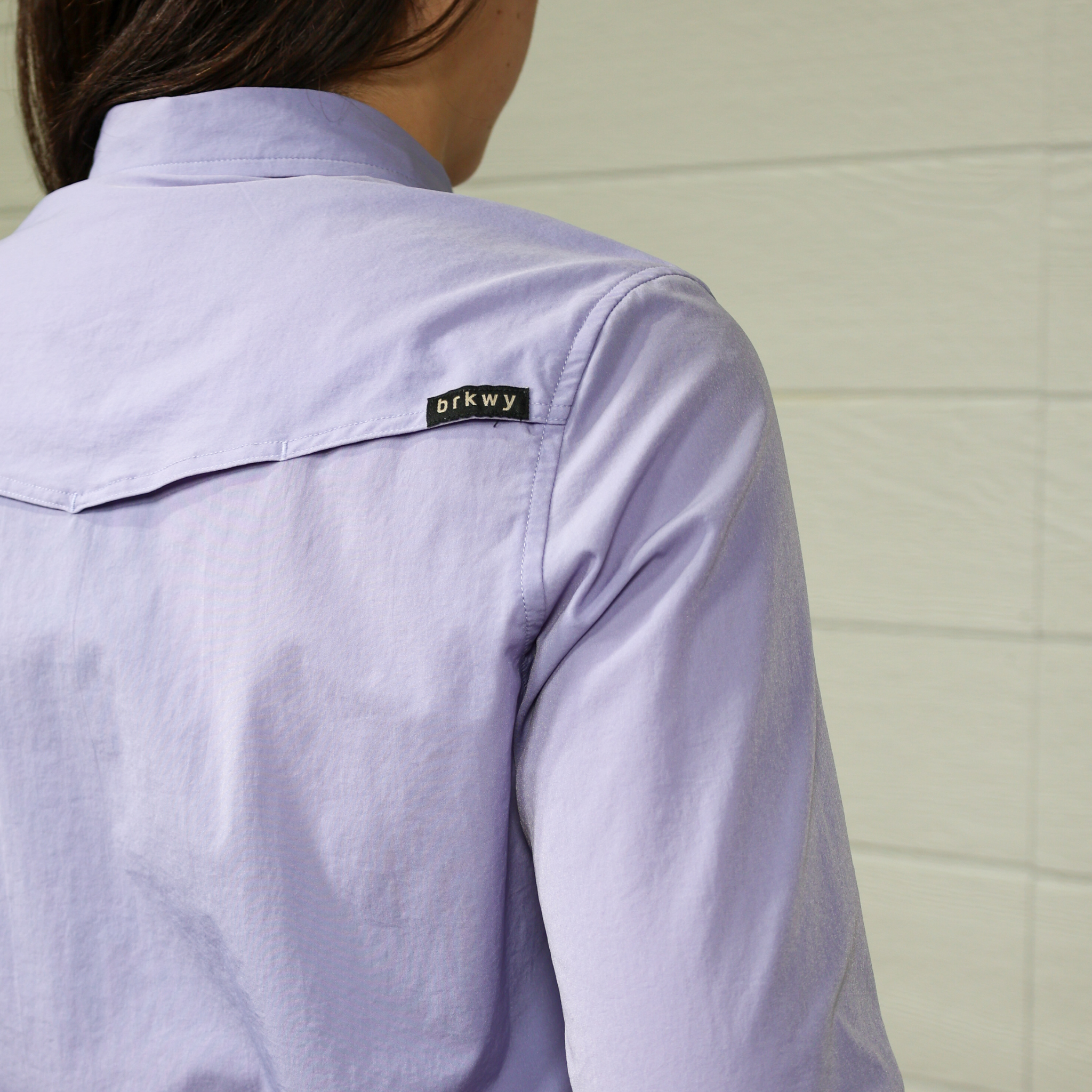 Person wearing a light purple shirt with a brkwy  logo on back. back facing